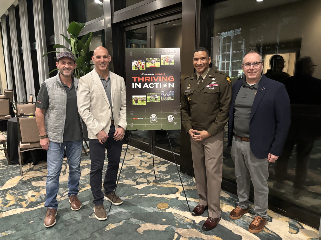 ZeroMils and partners gather beside a Military Thriving display at the American Bowl reception.
